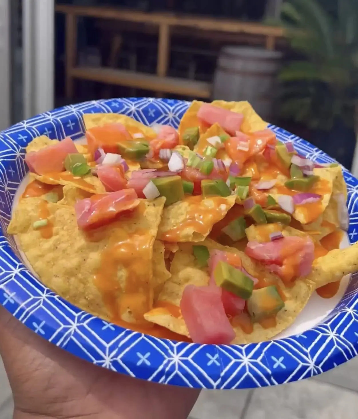 a plate of nachos with pico and avocado