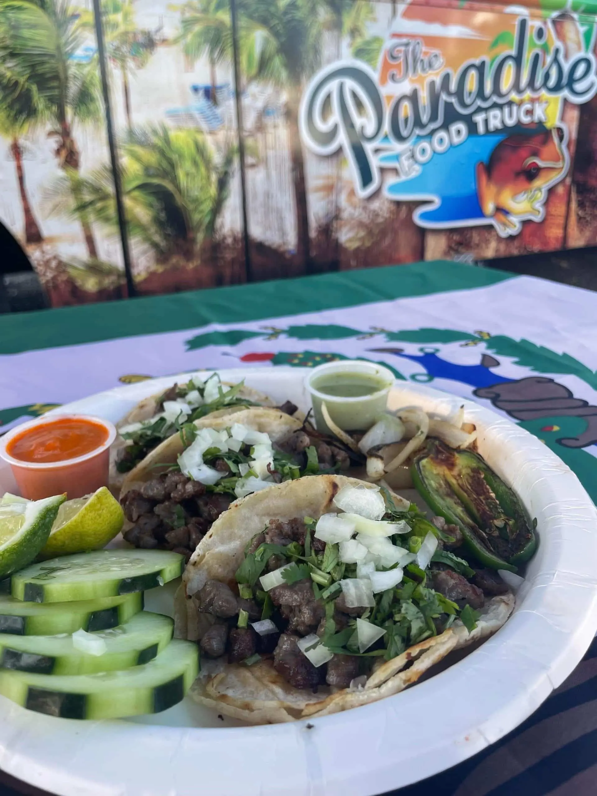 a plate of tacos al pastor with cucumber and dipping sauces