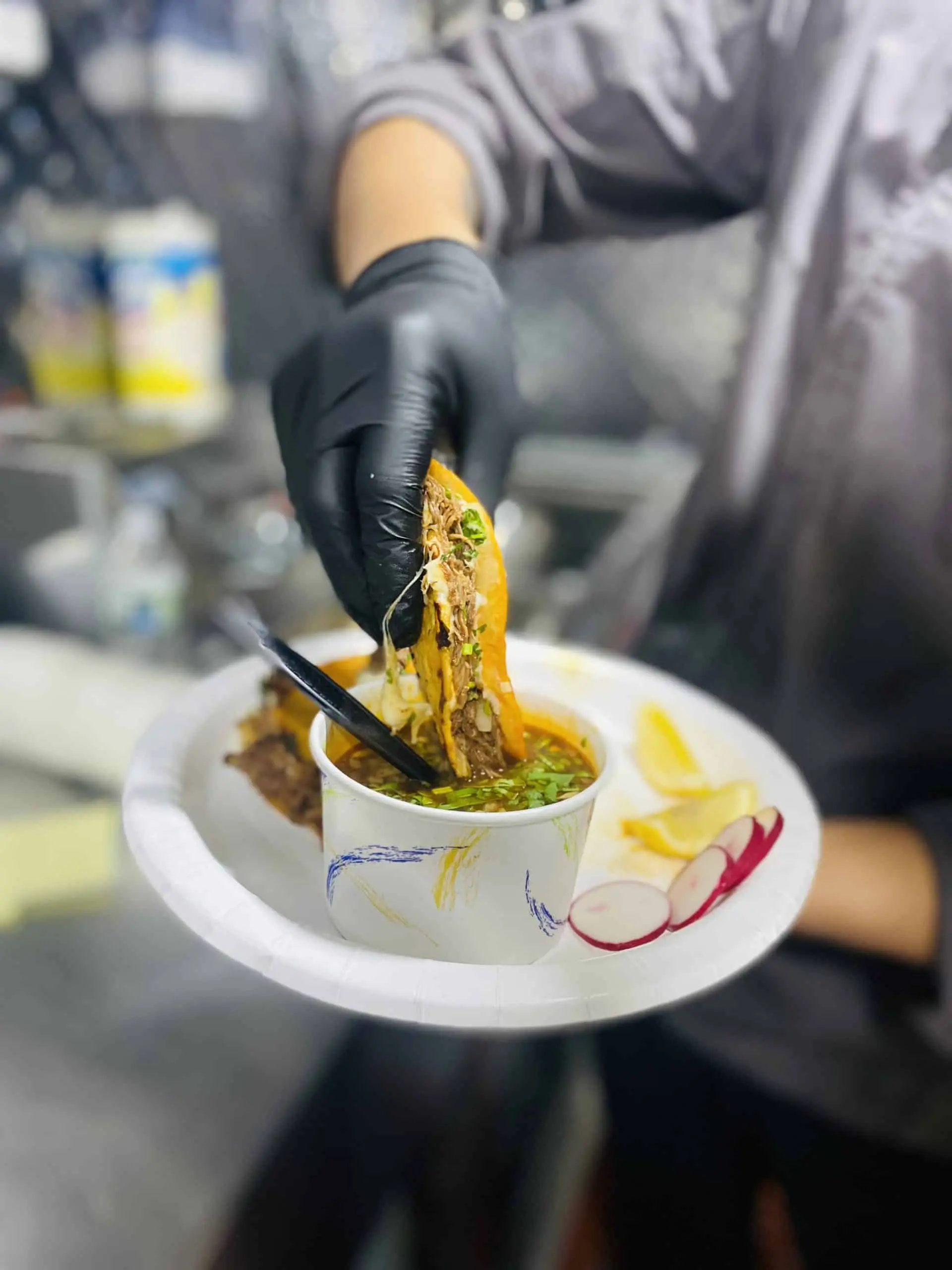 birria tacos being dipped in broth